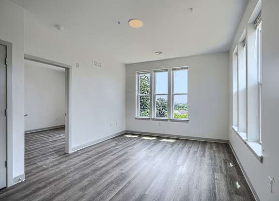 A large empty room with wooden floors and white walls.