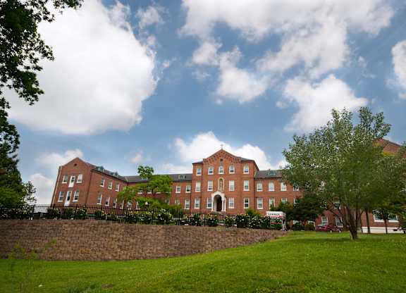 A large red brick building with a green lawn in front.
