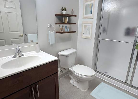 A bathroom with a toilet, sink, and mirror.