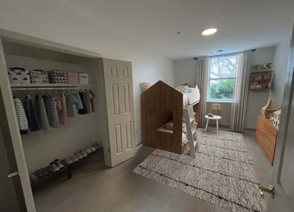A baby's room with a crib, a changing table, and a closet with baby clothes.
