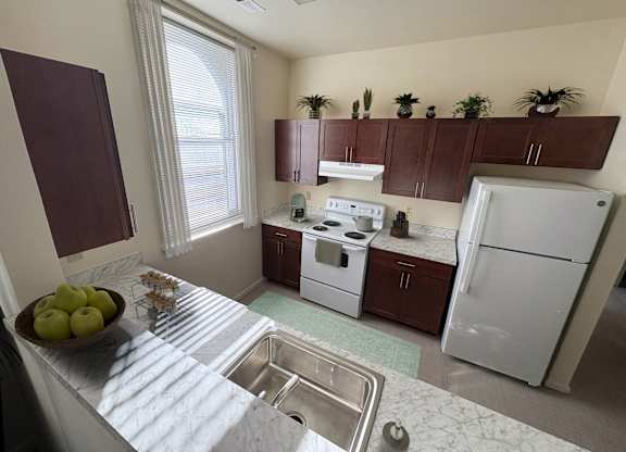 A kitchen with a white fridge and a bowl of apples on the counter.