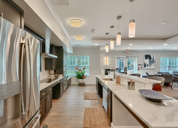 an open kitchen and living room with stainless steel appliances and white counter tops
