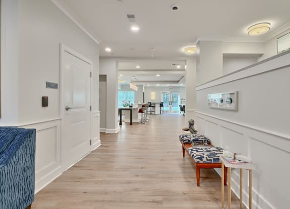 a long hallway with white walls and wood flooring and a long row of chairs