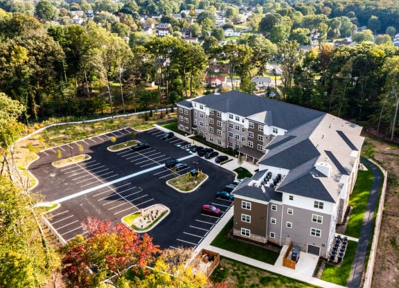 an aerial view of a building with parking lot and trees
