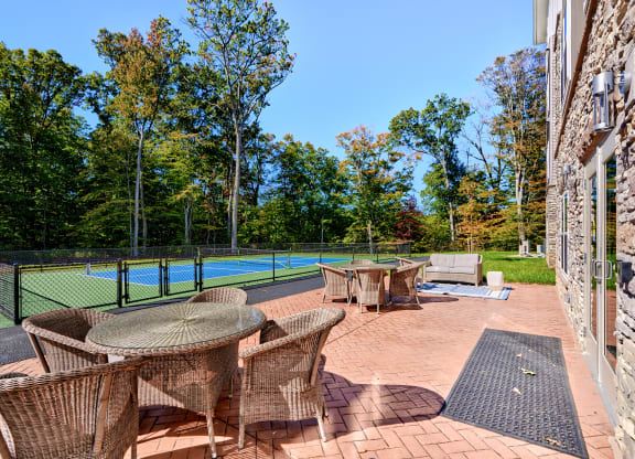 the backyard has a tennis court and a patio with tables and chairs