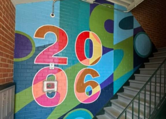 A staircase with a colorful 2016 mural on the wall.