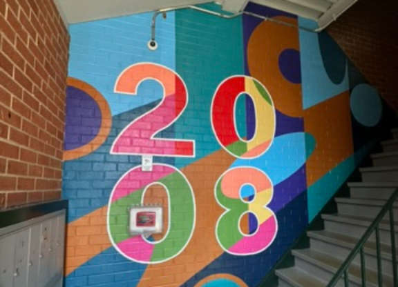 A staircase with a colorful 2018 mural on the wall.