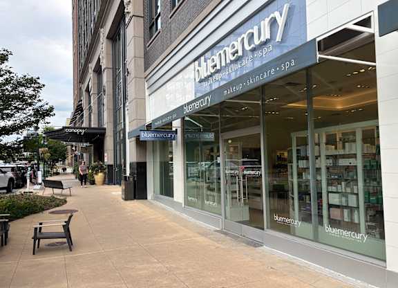A Blumercury storefront with a bench outside.