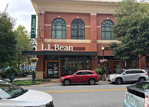 A red car is parked in front of the L.L. Bean store.