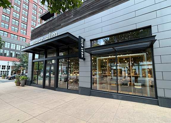 The front of a West Elm store with a black awning and glass doors.