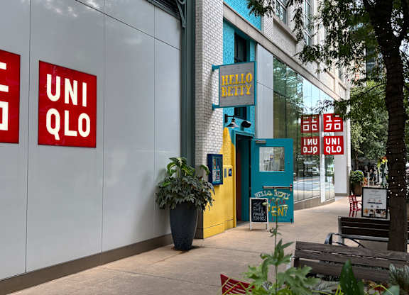 A UNIQLO storefront with a potted plant in front.