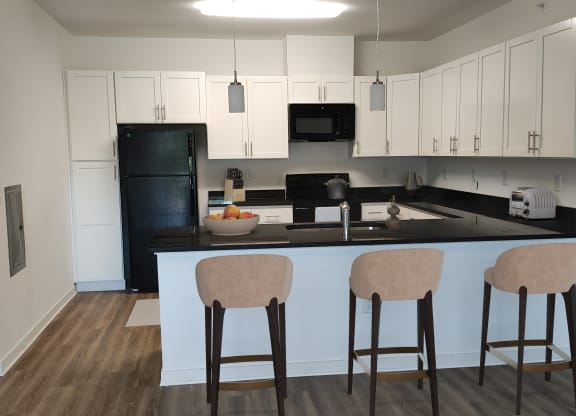 a kitchen with white cabinets and a large island with three stools
