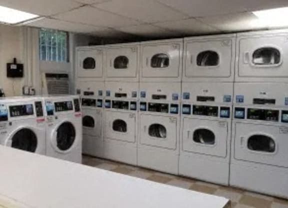 a laundry room filled with lots of white washers and dryers