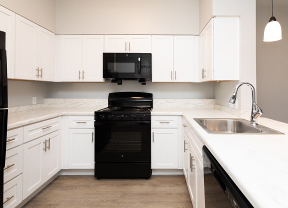 a kitchen with white cabinets and black appliances and a sink