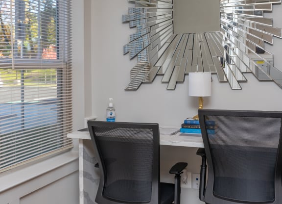two chairs in front of a desk with a mirror on the wall