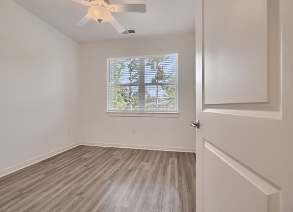 an empty bedroom with a window and a ceiling fan