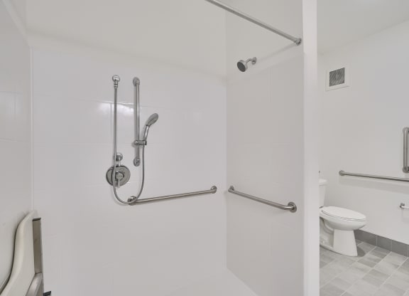 a handicap accessable white bathroom with grab bars and a toilet
