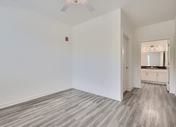 a living room with white walls and wood flooring and a ceiling fan