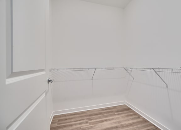 the closet in a small room with white walls and wood flooring