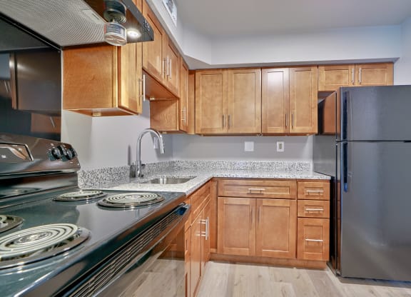 Kitchen of one bedroom with wooden cabinets and stainless steel appliances