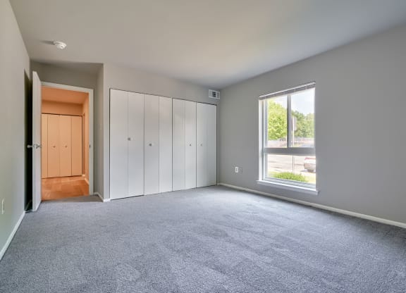 One bedroom with carpet a large window and a large closet