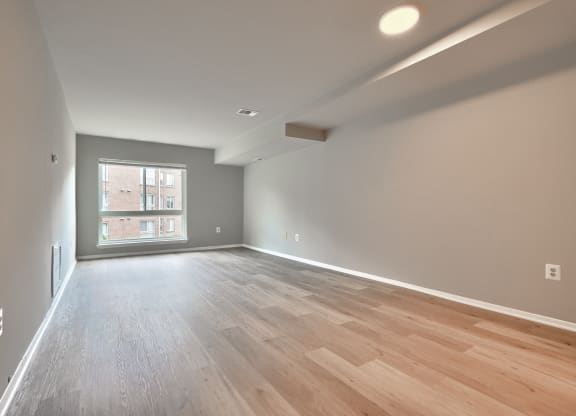 an empty living room with wood flooring and a window