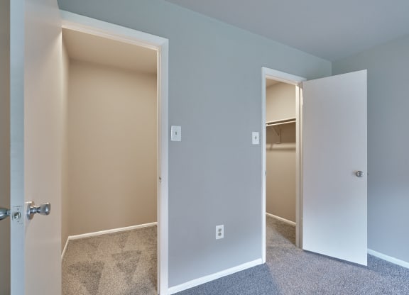 an empty bedroom with an open door to a closet