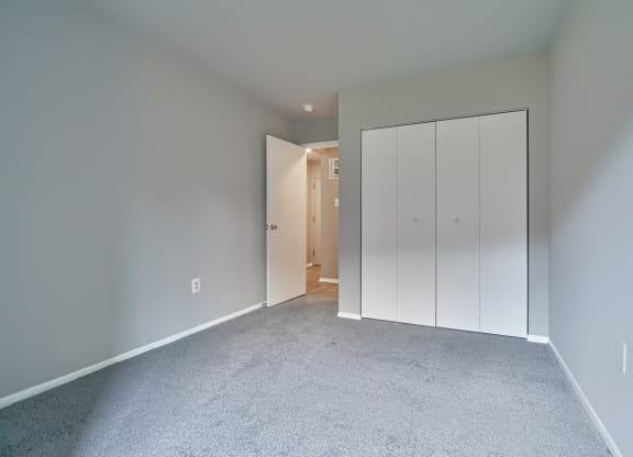 a bedroom with a closet and a carpeted floor