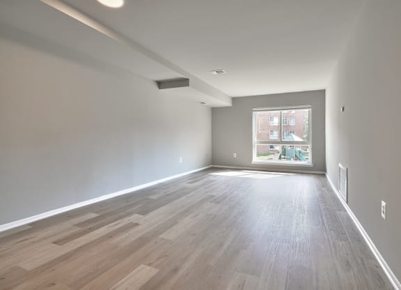 an empty living room with wood floors and a window