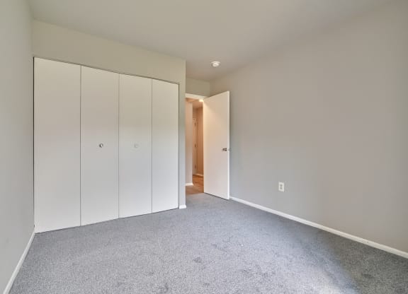 a bedroom with white cabinets and carpet and a door to a hallway