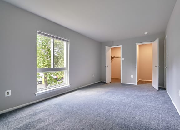 an empty bedroom with a large window and a door to a closet