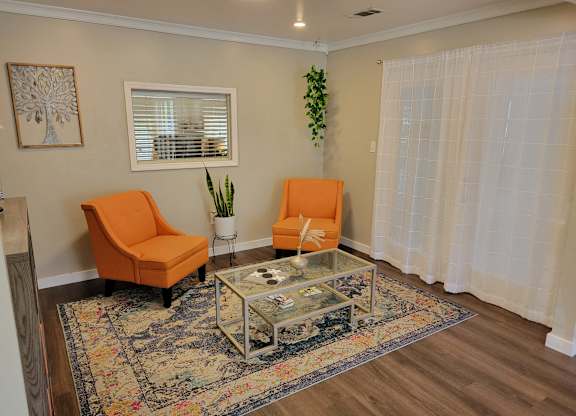 a living room with two orange chairs and a glass coffee table