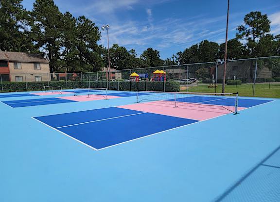 a group of tennis courts are painted in blue and pink
