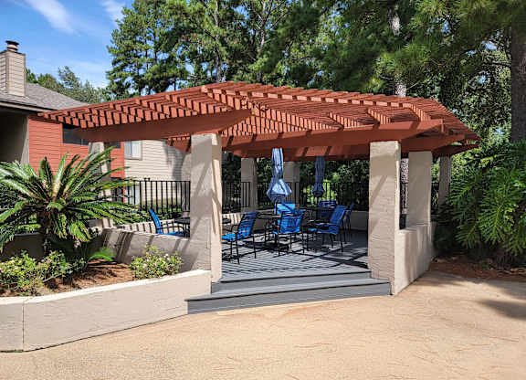 a covered patio with chairs and a pergola