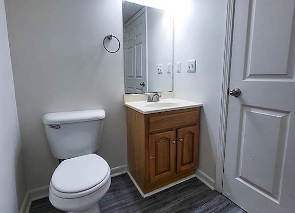 A bathroom with a toilet, sink and mirror.