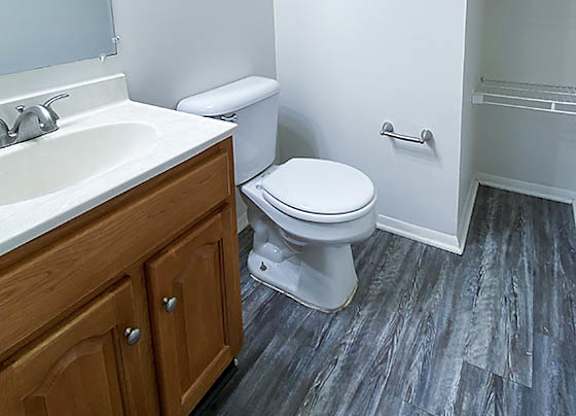 A bathroom with a toilet, sink, and wooden cabinet.