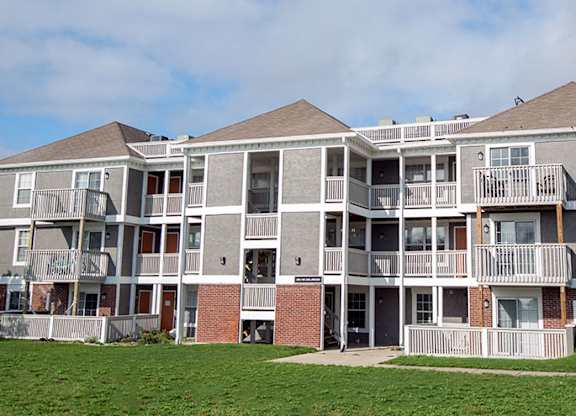 a large apartment building with balconies and a lawn