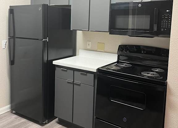 a kitchen with a stove refrigerator and microwave