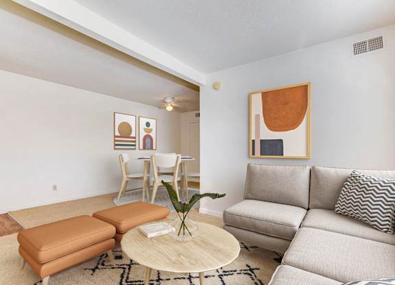 A living room with a couch, chair, and a table with a plant on it.