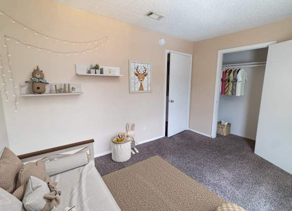 A room with a bed, a couch, a rug, and a painting of a deer on the wall.