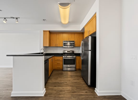 an empty apartment kitchen with black countertops and stainless steel appliances