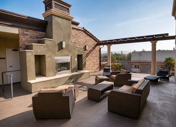 A patio with a fireplace and wicker furniture.