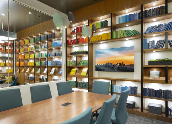 One-Bedroom Apartments in Woodland Hills, CA - The Q Variel Apartments - Library Room with Carpet Flooring, Chairs, Tables, and a Bookshelf Filled with Books, Vinyl Records, and Modern Décor