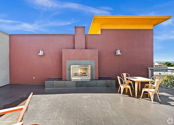 A patio with a fireplace and chairs.