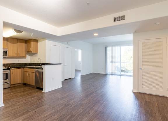 A spacious kitchen with wooden floors and white cabinets.