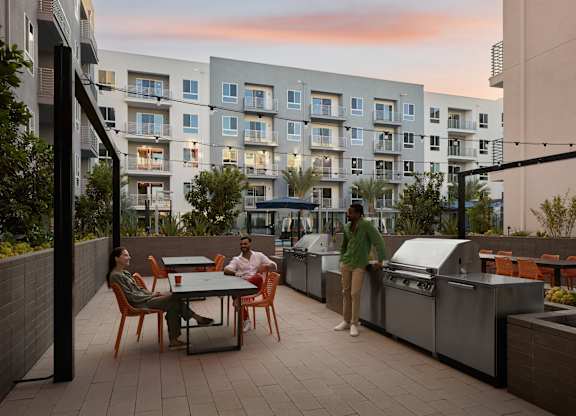 Two people are standing on a patio with a grill.