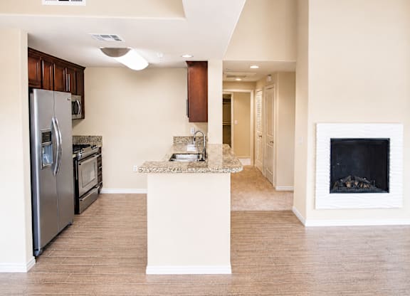 A kitchen with a refrigerator, oven, and sink.