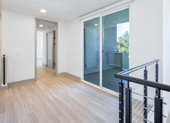 a renovated living room and hallway with sliding glass doors to a balcony
