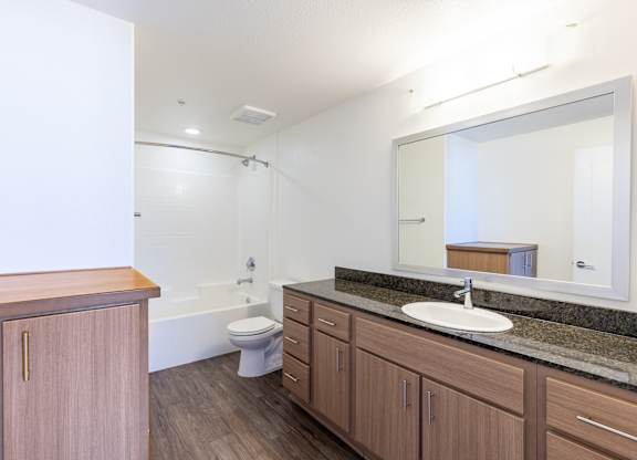 A bathroom with a sink, toilet, and mirror.