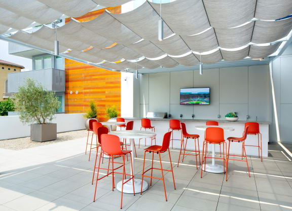 a dining area with red chairs and tables under a white canopy
